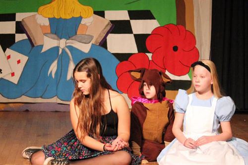 3 students sitting on stage during a play